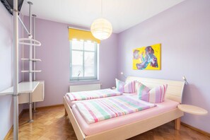 Un dormitorio con una cama, una ventana, un cuadro y una silla.