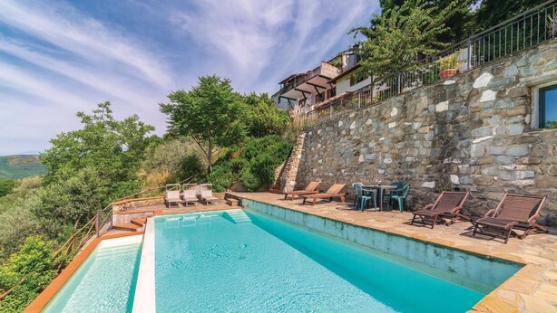 A rectangular swimming pool with a stone deck, surrounded by lounge chairs and a stone wall. - Nice apartment in Loro Ciuffenna AR (Loro Ciuffenna AR)