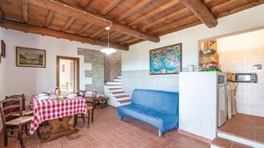 A dining area with a checkered tablecloth, wooden chairs, a blue sofa, and a staircase leading to an upper level. - Nice apartment in Loro Ciuffenna AR (Loro Ciuffenna AR)