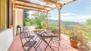 A covered outdoor patio with a table set for breakfast, chairs, and a view of the surrounding landscape. - Nice apartment in Loro Ciuffenna AR (Loro Ciuffenna AR)