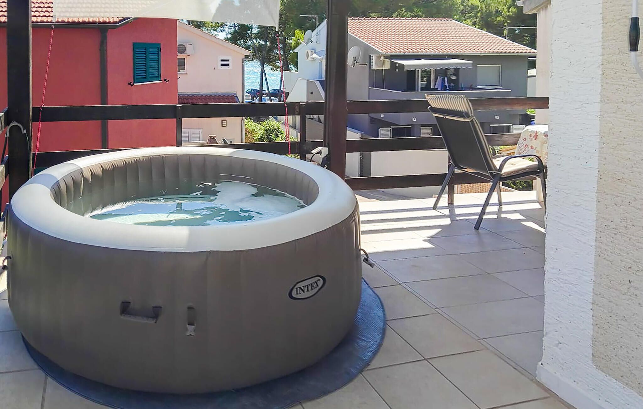 Un jacuzzi sur un balcon, avec une chaise et une table à proximité.