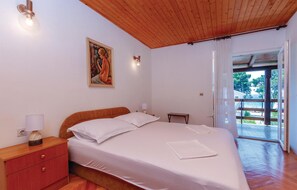 A bedroom with a wooden ceiling, a bed with white linens, a nightstand with a lamp, and a painting on the wall. - Nice apartment in Jadrija with house sea view (Jadrija)
