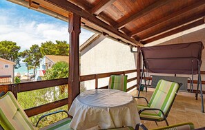 A covered outdoor seating area with a table and chairs, overlooking a body of water and buildings. - Nice apartment in Jadrija with house sea view (Jadrija)