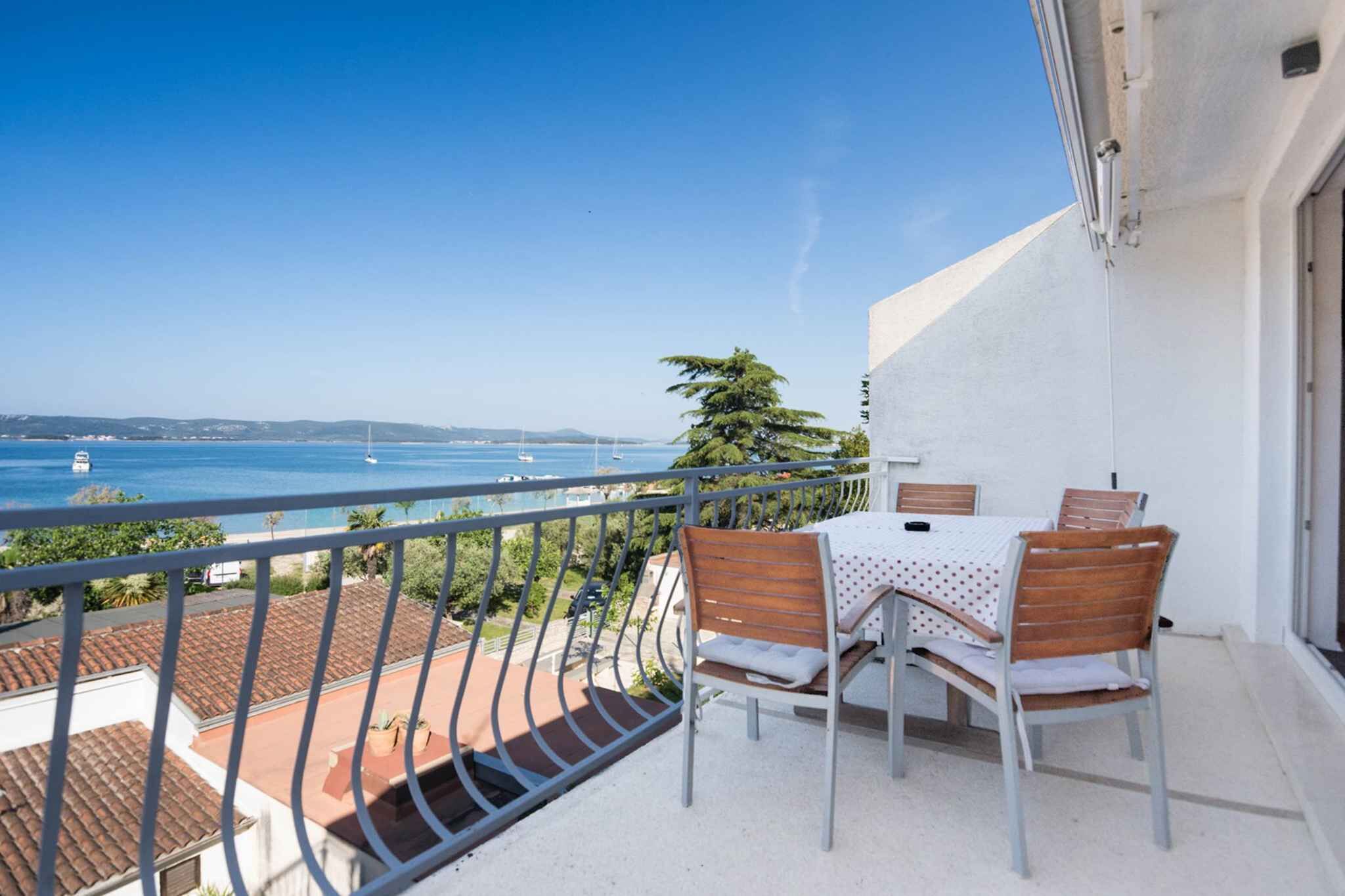 Ein Balkon mit Tisch und Stühlen mit Blick auf die Küste.