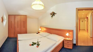 Een slaapkamer met een houten bed, nachtlampjes, een hanglamp, een kledingkast en een spiegel.