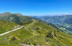 Un paisaje montañoso con cielo despejado, un camino sinuoso y un edificio con vistas panorámicas.