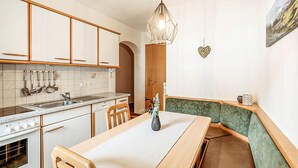 Een compacte keuken met moderne apparatuur, een eethoek met een bank en een hanglamp.