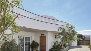 A modern house with a white exterior, a wooden door, and a balcony with blue railings.