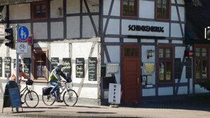Un edificio tradicional con entramado de madera y un letrero que dice "SCHINKENKRUG", con una bicicleta estacionada al frente.