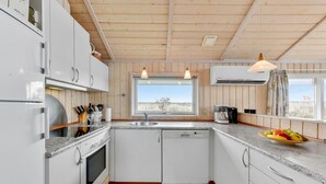 Cocina moderna con armarios blancos, horno empotrado, lavamanos y ventana con vistas al exterior.
