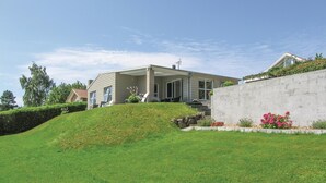 A modern house with a covered patio, a concrete retaining wall, and a well-maintained lawn. - Awesome home in Rudkøbing (Rudkøbing)