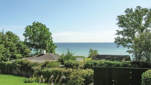 A coastal property with a view of the sea, a fenced garden, and a small wooden structure. - Awesome home in Rudkøbing (Rudkøbing)