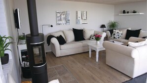 A modern living room with a sofa set, a coffee table, and a black wood-burning stove. - Awesome home in Rudkøbing (Rudkøbing)