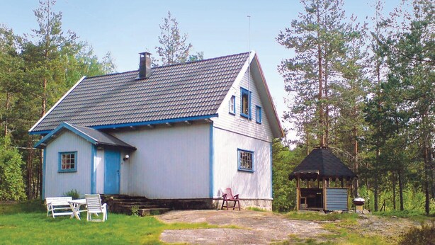 A two-story house with a sloped roof and a chimney, surrounded by trees.
