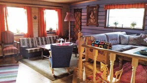 A cozy living room with a sofa, chairs, a table, and a wooden chair with a horse design.