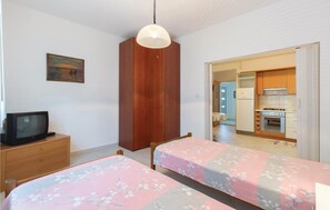 A bedroom with two beds, a wooden wardrobe, a television on a dresser, and a painting on the wall. - 1 bedroom beautiful apartment in Zadar (Zadar)