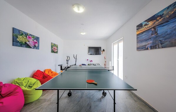 A room with a ping pong table, colorful bean bags, a TV, and artwork on the walls. - Lovely home in Podpican (Podpican)