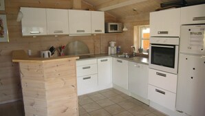 A compact kitchen with white cabinets, a microwave, an oven, and a refrigerator. - Amazing home in Tranekær with sauna (Tranekær)