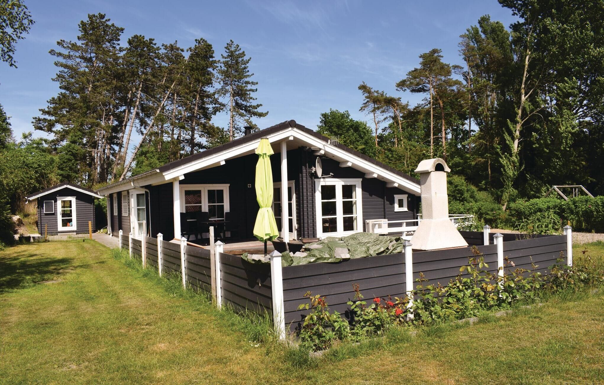 Une cabane avec une véranda, une cheminée et une cour clôturée.