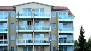 Een meerlaags woongebouw met balkons, een plat dak en een centrale ingang.