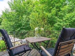 A wooden deck with two black cushioned chairs and a small table with a vase of flowers. - WR-02 - Villa Waldrose Curr. WR-02 (Kühlungsborn)