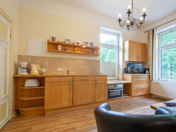 A modern kitchen with wooden cabinets, a built-in oven, and a coffee maker. - WR-02 - Villa Waldrose Curr. WR-02 (Kühlungsborn)