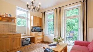 Eine moderne Küche mit Holzausbau, einem Einbauofen und einem Essbereich mit einem roten Sofa und einem Holztisch.