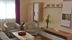 A modern living room with a sofa, two armchairs, a coffee table, a cabinet, and a small side table with a vase of flowers.