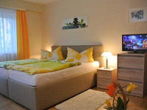 A bedroom with a bed, bedside table, lamp, TV, and a painting on the wall. - Apartment on the Wiesent - Apartment An der Wiesent (Ebermannstadt)