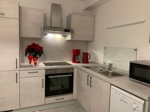 A modern kitchen with a built-in oven, a microwave, a coffee maker, and a stainless steel sink. - Apartment on the Wiesent - Apartment An der Wiesent (Ebermannstadt)