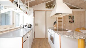 A modern kitchen with white cabinets, a granite countertop, a built-in oven, and a large window. - Nice home in Blokhus with kitchen (Blokhus)