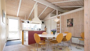A modern kitchen with wooden beams, a dining area with yellow chairs, and a central island. - Nice home in Blokhus with kitchen (Blokhus)