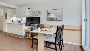 A modern kitchen with white cabinetry, a dining table with chairs, a flat-screen TV, and a pendant light. - 1 bedroom gorgeous apartment in Fanø (Fanø)