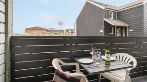 An outdoor seating area with a table and chairs, a bottle of Zantsi wine, and a flag in the background. - 1 bedroom gorgeous apartment in Fanø (Fanø)