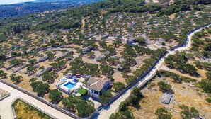 Vue aérienne d’une propriété comprenant une piscine, une maison et un mur en pierre.