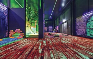 A hallway with a red wooden floor, a green wall with a tree mural, and a brick wall with a green door. - Cozy home in Thale with sauna (Thale)