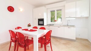 Una cocina moderna con armarios blancos, una estufa a gas y un ventanal con vistas al verdor.