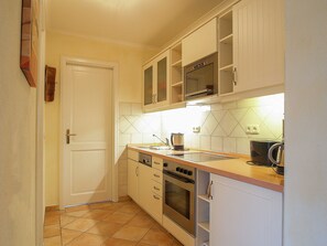 Una cucina compatta con mobili bianchi, un forno a microonde, un forno e un lavello.