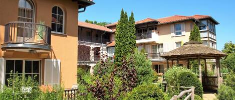 A hotel with multiple balconies, a wooden deck, and lush greenery.