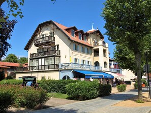 Um edifício de dois andares com varanda, área de estar coberta ao ar livre e placa de restaurante.