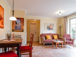 Ein Wohnzimmer mit Essbereich, einer Couch mit gestreiften Kissen, einem Holztisch und einem Gemälde an der Wand.