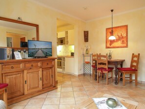 Una camera d'albergo con un armadio in legno, una televisione, un tavolo da pranzo con sedie e un angolo cottura.