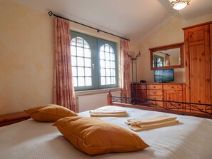 A bedroom with a bed, two pillows, a dresser, a mirror, and a window with curtains. - Residence Laguna Whg L-06 .. - L-06 (Kühlungsborn)