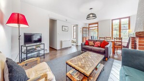 A living room with a TV, sofa, coffee table, and lamp. - Appartement jolie vue rivière (Jaulgonne)
