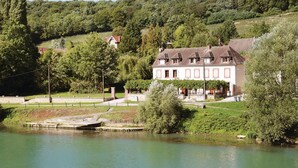 Ein großes, zweistöckiges Haus mit Garten und Teich vor der Fassade.