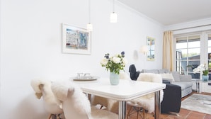 A modern dining area with a white table, fluffy chairs, and a vase of flowers. - Kampen-Kliff 3 from A&M - Kampen-Kliff 3 (Kampen (Sylt))