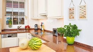 A modern kitchen with white cabinets, a granite countertop, a dishwasher, a toaster, and a potted plant. - Kampen-Kliff 3 from A&M - Kampen-Kliff 3 (Kampen (Sylt))