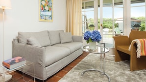 A living room with a striped sofa, a glass coffee table with blue flowers, a brown armchair, and a clear glass table with books. - Kampen-Kliff 3 from A&M - Kampen-Kliff 3 (Kampen (Sylt))