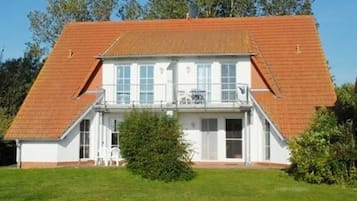 Ein zweistöckiges Gebäude mit einem geneigten Dach, großen Fenstern und einem kleinen Balkon.