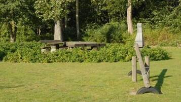 Ein Picknicktisch in einer grünen Parkanlage mit Bäumen im Hintergrund.